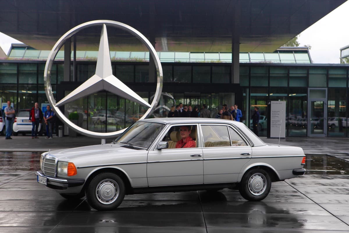 Silberner W123 vor dem Mercedes-Stern in Sindelfingen
